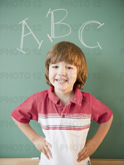 Hispanic boy standing underneath abcÕs on blackboard