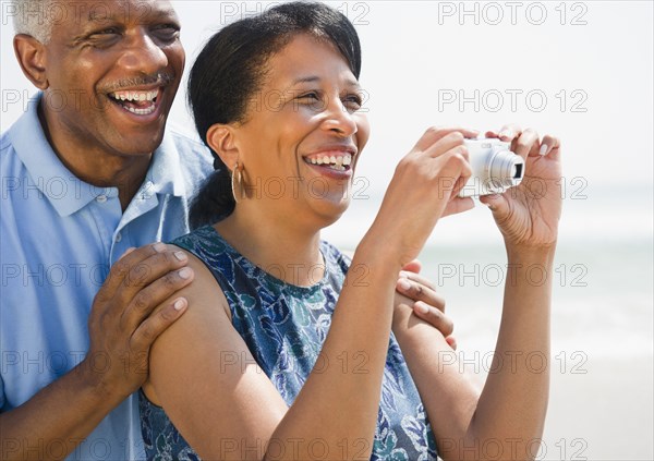 Black couple taking pictures on beach