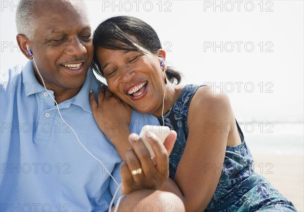 Black couple on beach listening to music together