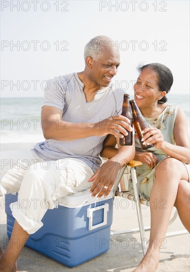 Black couple drinking beer on beach