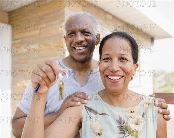 Proud Black couple holding keys to new home