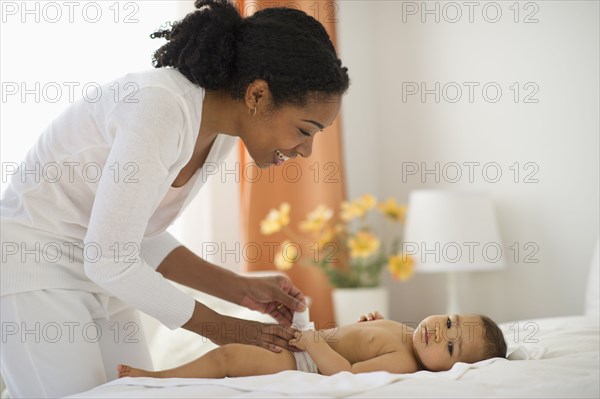 Mixed race mother changing babyÕs diaper