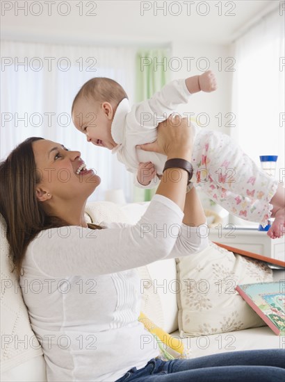 Smiling mother lifting baby