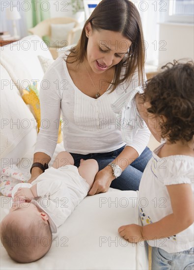 Mother changing baby's diaper on sofa