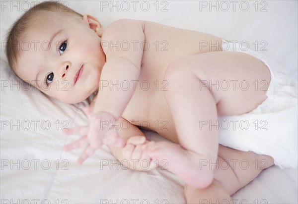 Mixed race baby laying on bed