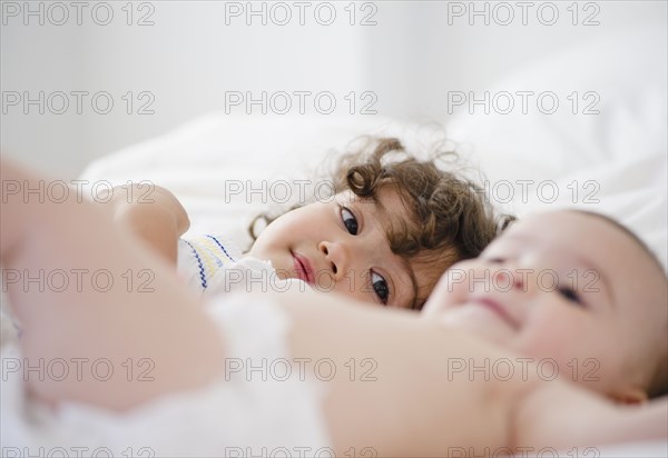 Mixed race girl watching baby sister on bed