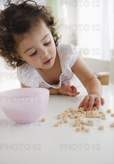 Mixed race girl picking up spilled cereal