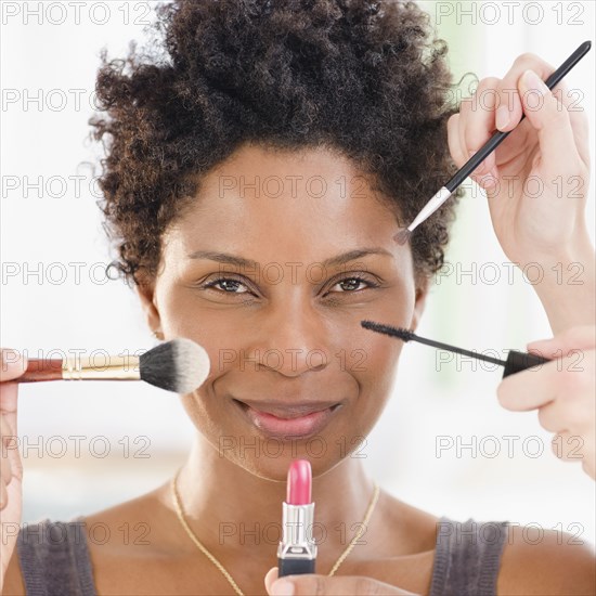 People putting makeup on Black woman