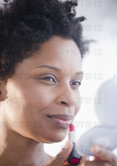 Black woman putting on lipstick