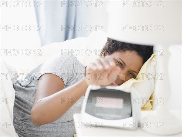 Black woman turning off morning alarm