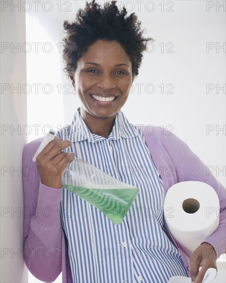 Black woman holding paper towels and spray bottle