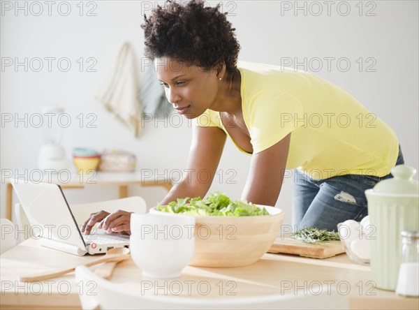 Black woman using laptop on dining room table