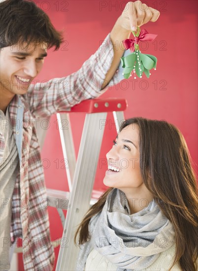 Man holding mistletoe over wife's head