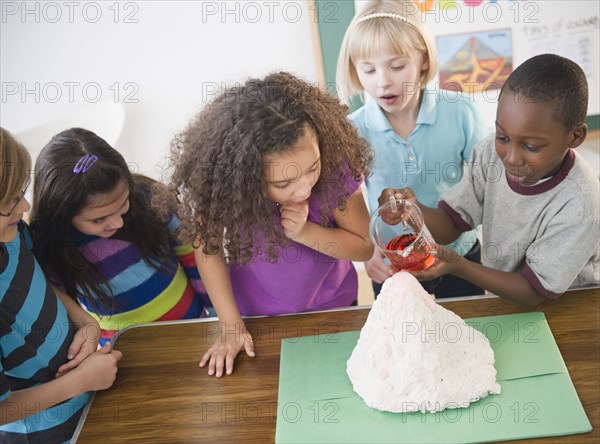 Children watching boy with model volcano