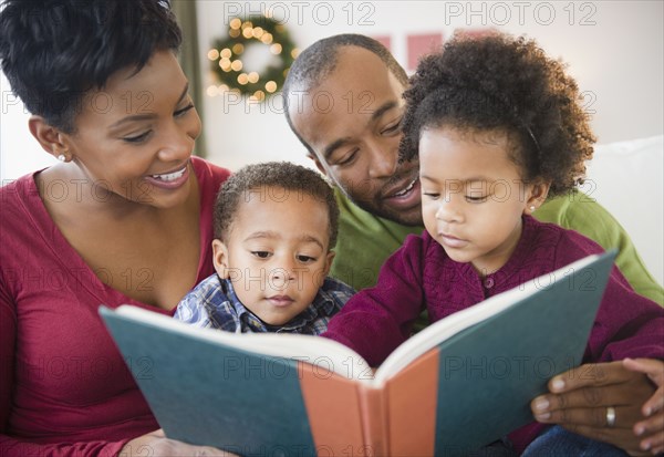 Black family reading book together