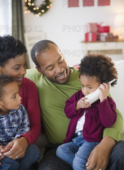 Black family watching girl talking on telephone