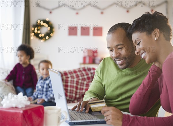 Black mother and father shopping online with credit card