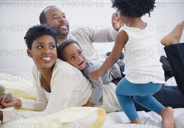 Black family laying on bed together