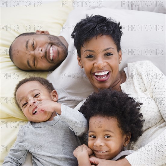 Black family laying on bed together