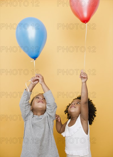 Black children holding helium balloons