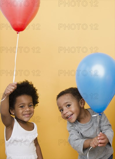 Black children holding helium balloons