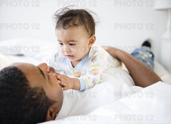 Father laying on bed with baby boy