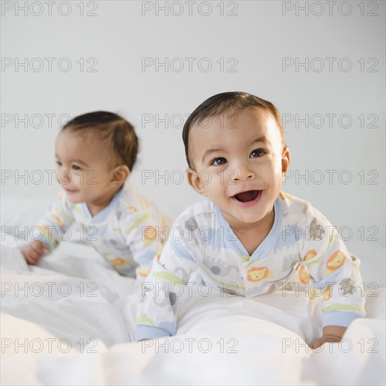 Mixed race twins crawling on bed