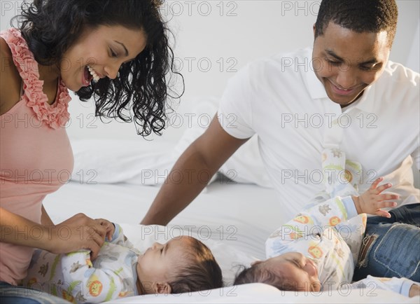 Parents playing on bed with baby twins