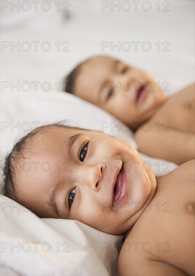 Smiling mixed race twins laying together