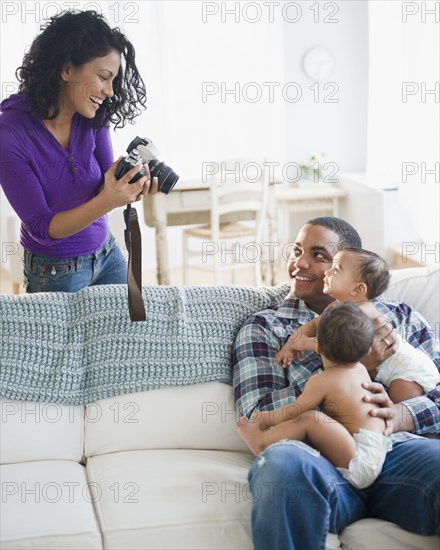 Mother taking picture of father holding twin baby boys