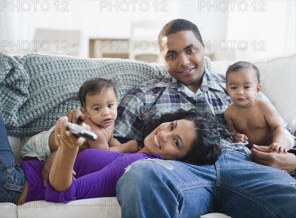 Parents and twin baby boys watching television together