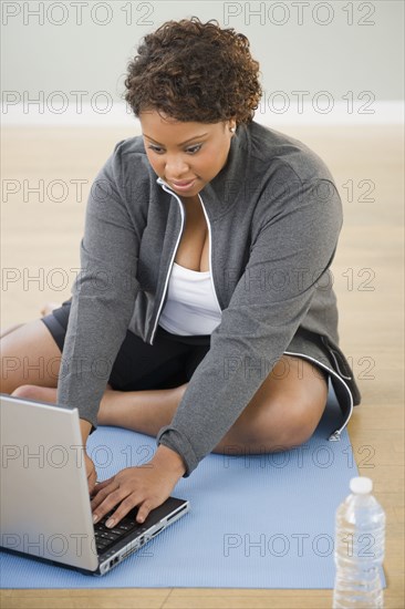 African American woman sitting on floor using laptop