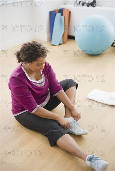 African American woman sitting on floor putting on shoes