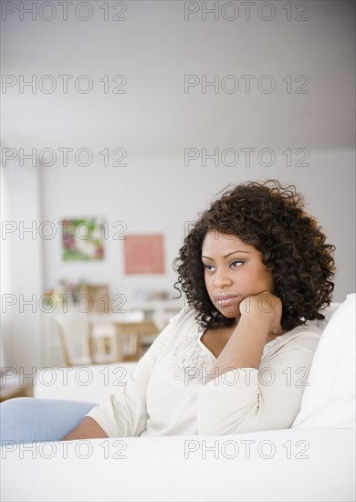 Sad African American woman sitting on sofa