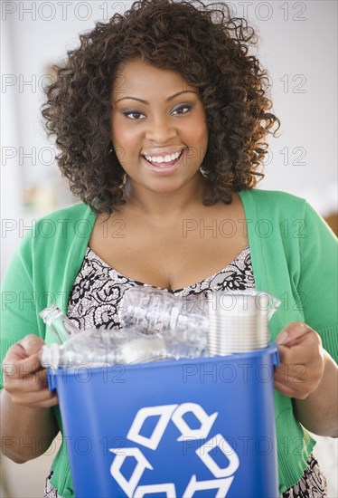 African American woman carrying recycling bin