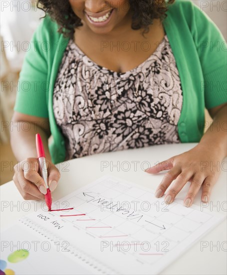 African American woman crossing off days on calendar