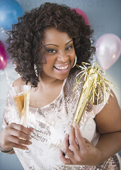 African American woman with noise maker and glass of Champagne