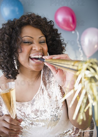 African American woman with noise maker and glass of Champagne