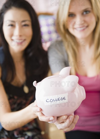 Friends holding piggy bank labeled with "college"