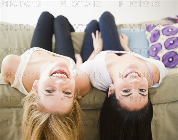 Friends laying on sofa upside-down