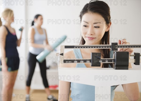 Asian woman weighing herself on scale