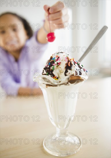 African American girl putting cherry ice cream sundae