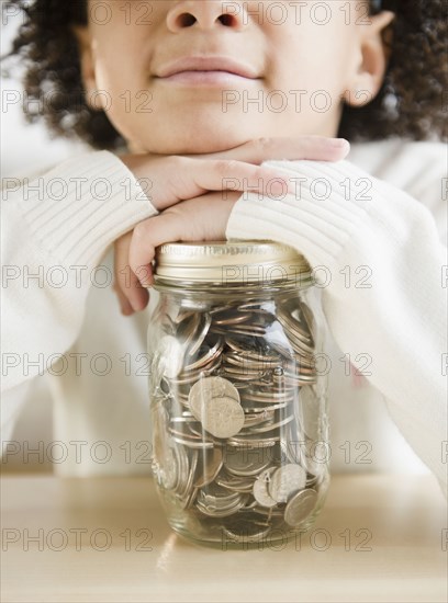 African American girl holding jar of coins