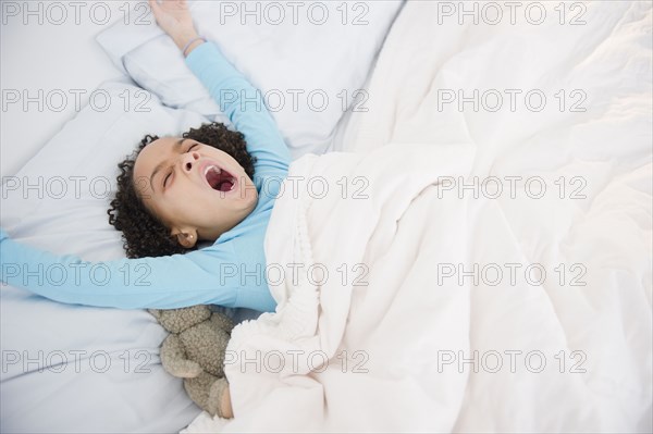African American girl waking up in bed