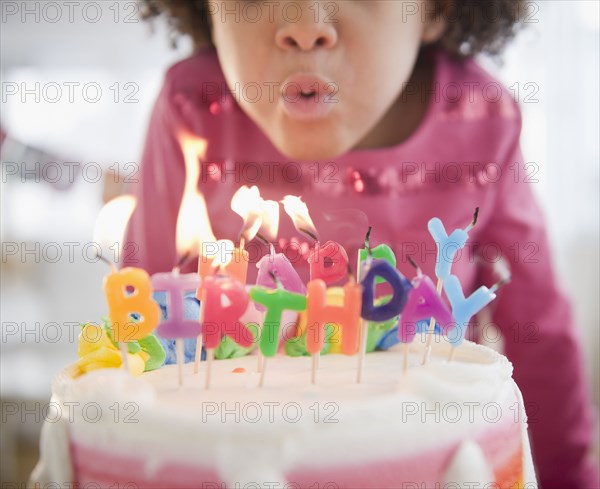 African American girl blowing out birthday candles