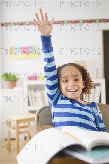 African American girl raising hand in classroom