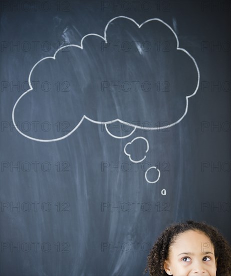 African American girl standing near thought bubble on blackboard