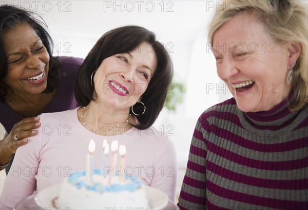 Women surprising friend with birthday cake