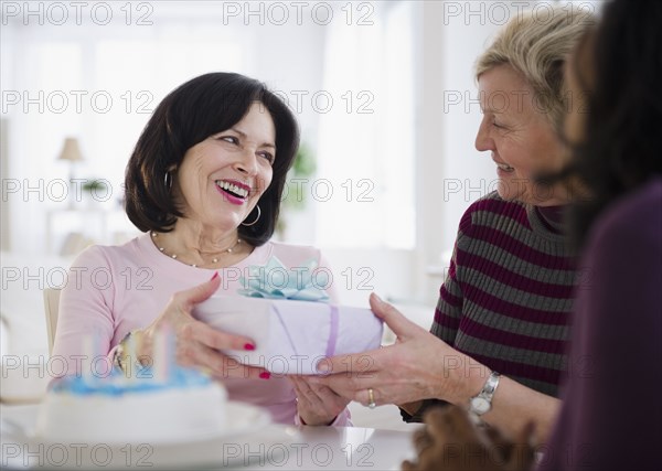 Women surprising friend with birthday cake and gift