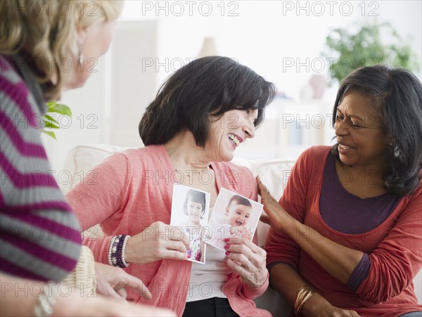 Woman showing friends photographs of her grandchildren